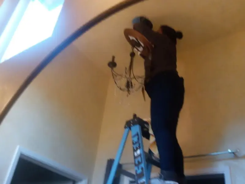 Electrician installing a chandelier in a Watauga residence